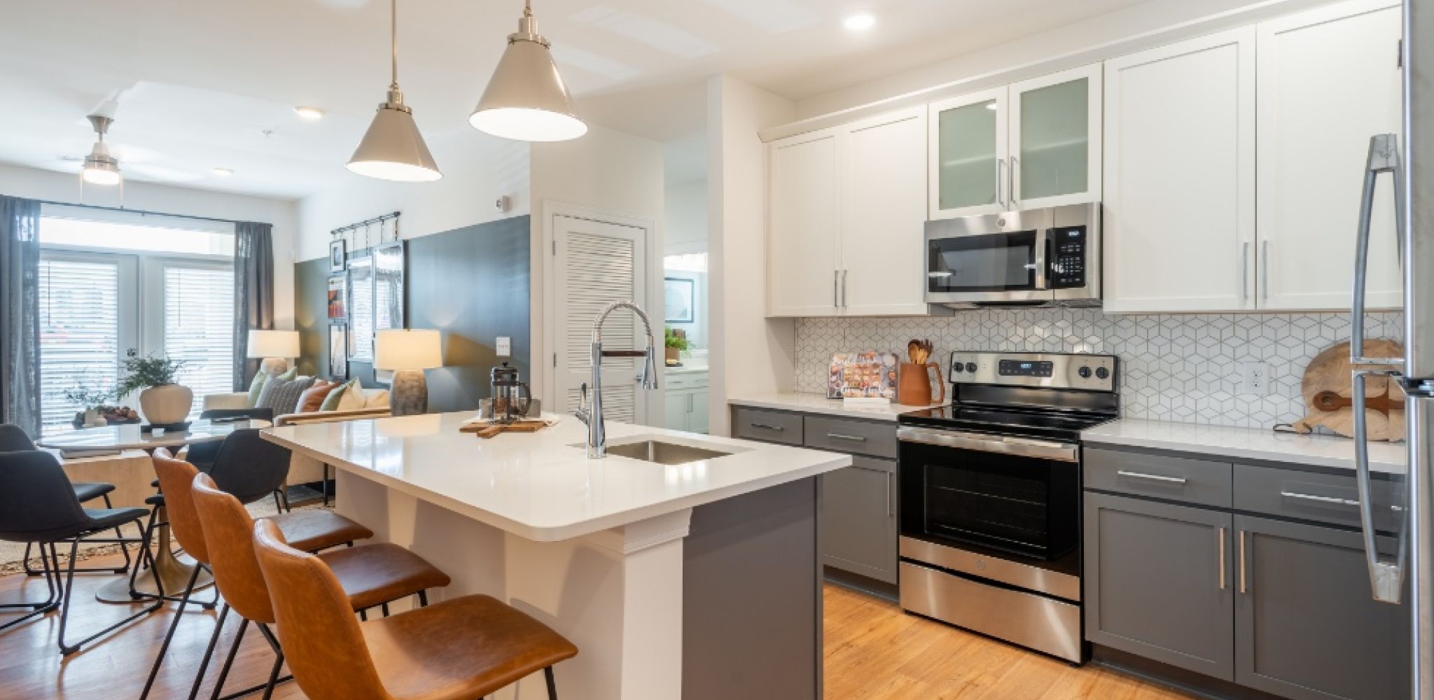 Hawthorne at Holly Springs luxury apartment kitchen with island, quartz countertops, designer tile backsplash, and stainless steel appliances