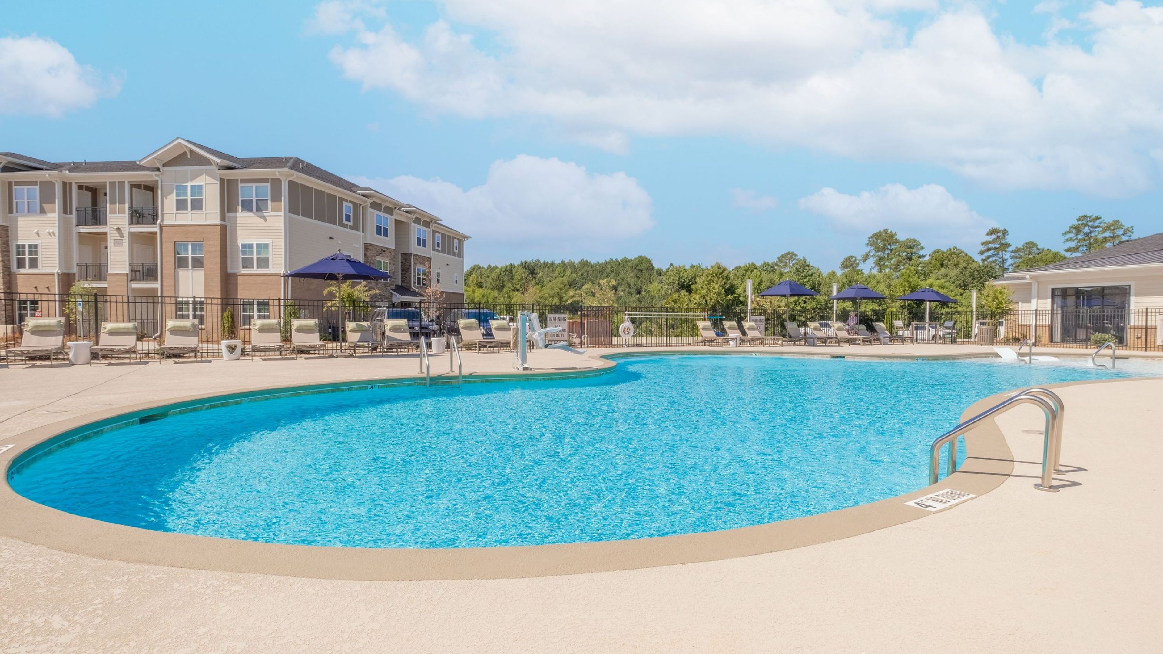 Hawthorne at Holly Springs luxurious outdoor pool with lounge seating, surrounded by apartment buildings